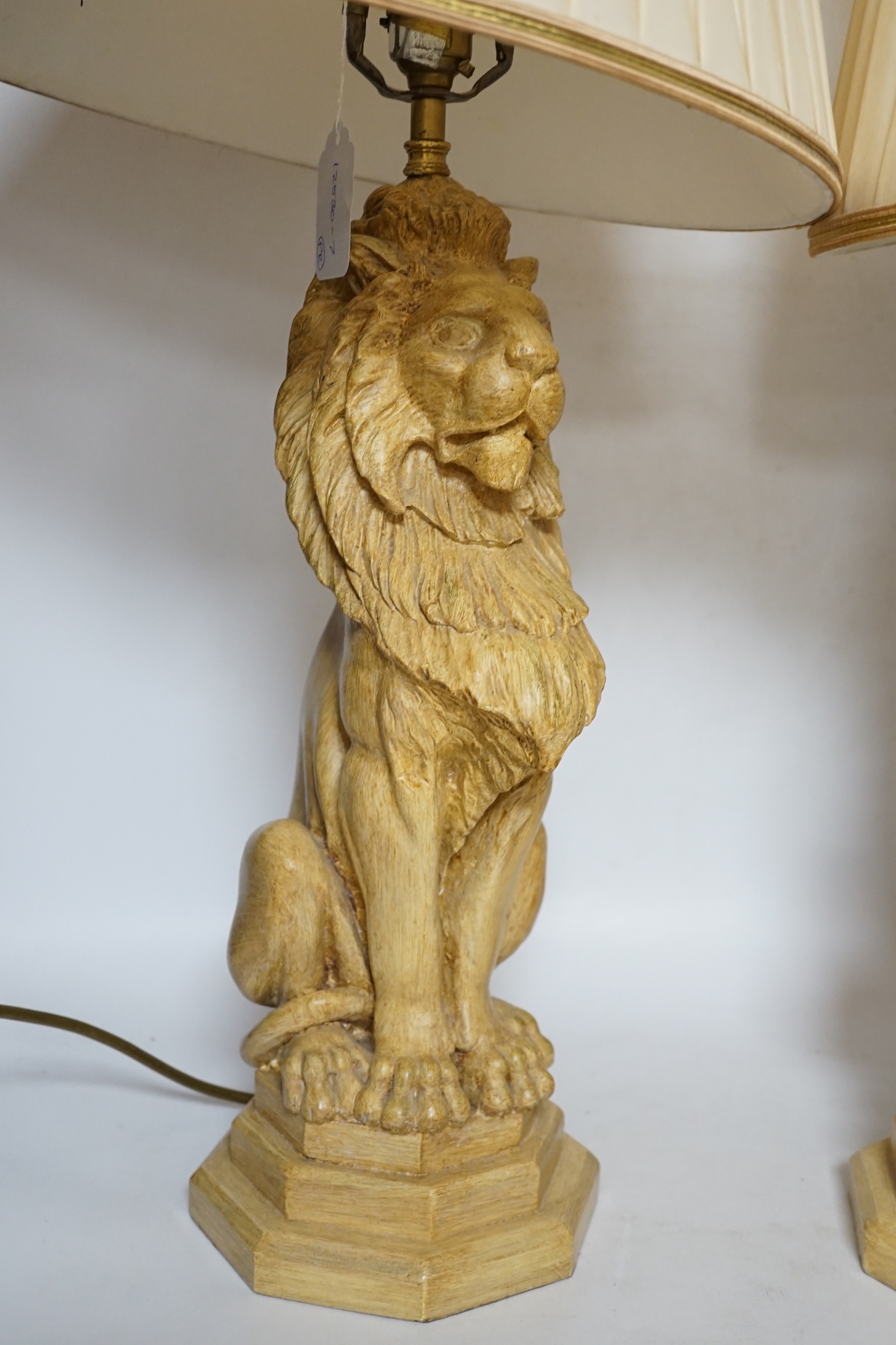 A pair of Thomas Blakemore composition lion lamps with cream shades, 64cm